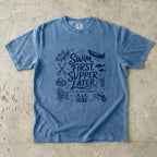 Swim First Supper Later Lake Vacation Shirt in Blue Jean – flat lay