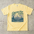Greetings from the Mountains Family Getaway Shirt in Butter – flat lay